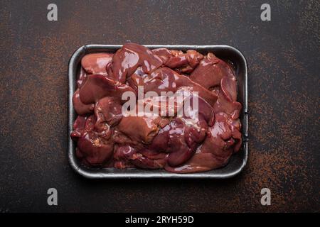 Foie de poulet cru dans le plateau de supermarché noir vue de dessus sur la table de cuisine de fond en béton rustique foncé. Ingrédient alimentaire sain, Banque D'Images