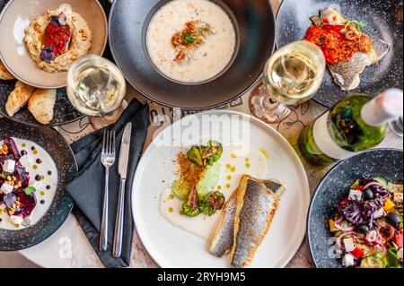 Un ensemble de plats de cuisine méditerranéenne sur une table dans un restaurant avec un verre et une bouteille de vin blanc. Vue d'en haut. Photo de haute qualité Banque D'Images