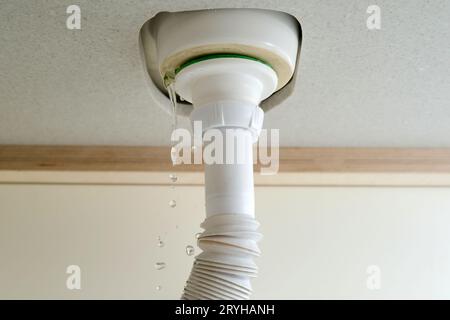 L'eau coule du tuyau sous l'évier, l'eau fuit à la maison dans la salle de bain Banque D'Images