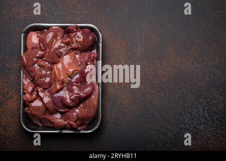 Foie de poulet cru dans le plateau de supermarché noir vue sur fond de béton rustique foncé table de cuisine. Ingrédient alimentaire sain, source de fer, folate Banque D'Images