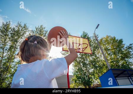 Courage in the Twilight : la résilience des filles rayonne dans un match de basket-ball en plein air Banque D'Images