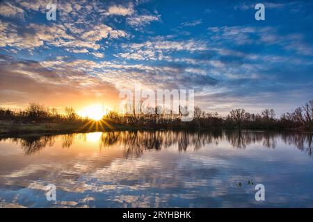 Belle vue sur le lac étincelant sous le coucher du soleil dans la campagne Banque D'Images