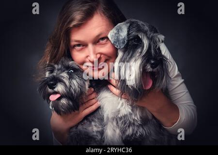 Portrait d'une femme heureuse avec deux chiots schnauzer miniatures Banque D'Images