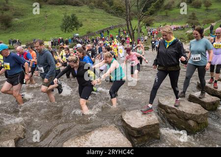 The Dovedale Dash, Thorpe, Derbyshire Peak District, Derbyshire, Angleterre, ROYAUME-UNI. 1 octobre 2023. Des concurrents courent dans le Dovedale Dash une piste de ski de fond de 4 3/4 miles partant du village de Thorpe dans le Derbyshire et dans la pittoresque vallée de Dovedale. Ici, les coureurs doivent traverser la rivière Dove soit en éclaboussant à travers la rivière ou via les tremplins bien connus. Le tableau de bord Dovedale ou le tableau de bord fonctionne depuis 1953. Crédit : Alan Keith Beastall/Alamy Live News Banque D'Images