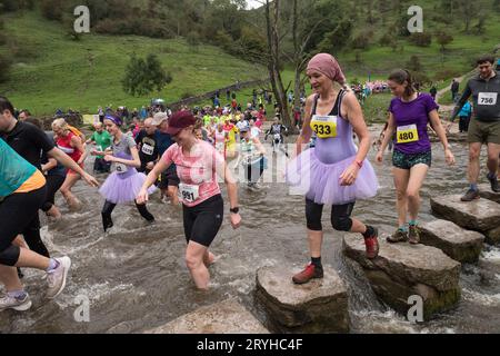 The Dovedale Dash, Thorpe, Derbyshire Peak District, Derbyshire, Angleterre, ROYAUME-UNI. 1 octobre 2023. Des concurrents courent dans le Dovedale Dash une piste de ski de fond de 4 3/4 miles partant du village de Thorpe dans le Derbyshire et dans la pittoresque vallée de Dovedale. Ici, les coureurs doivent traverser la rivière Dove soit en éclaboussant à travers la rivière ou via les tremplins bien connus. Le tableau de bord Dovedale ou le tableau de bord fonctionne depuis 1953. Crédit : Alan Keith Beastall/Alamy Live News Banque D'Images