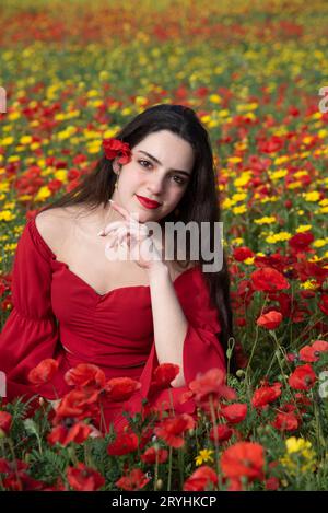 Portrait d'une jeune femme vêtue de rouge souriant sur le terrain au printemps. Banque D'Images