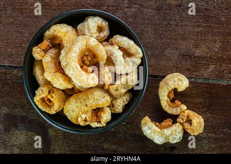 Vue de dessus de délicieuses couilles de porc frites maison croustillantes dans un bol en céramique noire. Banque D'Images