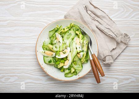 Saladier d'avocat vert sain avec œufs durs, concombres tranchés, haricots edamame, huile d'olive et herbes sur le dessus de la plaque en céramique vie Banque D'Images