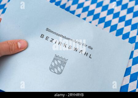 Augsbourg, Bavière, Allemagne - 29 septembre 2023 : enveloppe pour le vote par correspondance pour les élections municipales en Bavière et le 8 octobre 2023 devant un drapeau bavarois *** Umschlag zur Briefwahl für die Bezirkswahl in Bayern und Am 8 Oktober 2023 vor einer bayerischen Flagge Banque D'Images