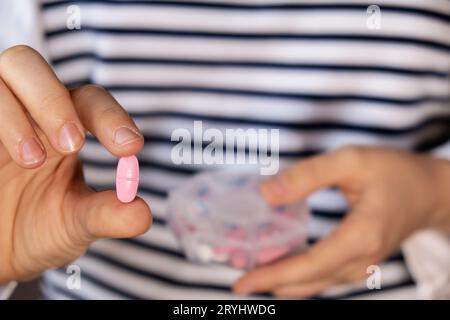 Femme trier les pilules Organiseur des injections hebdomadaires gros plan de la boîte de pilules médicales avec des doses de comprimés pour la journée prendre des médicaments avec des médicaments blancs roses et capsule Banque D'Images