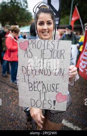 Manchester, Royaume-Uni. 01 octobre 2023. Un manifestant tient une pancarte avant le début de la marche. Des milliers de personnes défilent à travers la ville pour une manifestation nationale pendant la Conférence du Parti conservateur. Organisées par l'Assemblée des peuples et rejointes par les syndicats, les revendications comprennent la fin de la crise du coût de la vie et la défense du NHS. Crédit : Andy Barton/Alamy Live News Banque D'Images