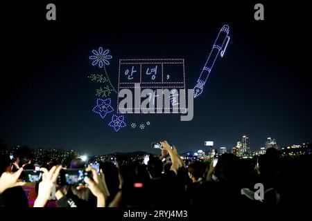 Séoul, Corée du Sud. 1 octobre 2023. Les gens regardent un spectacle lumineux de drone près de la rivière Hangang à Séoul, en Corée du Sud, le 1 octobre 2023. Un spectacle de lumière de drone avec 1 000 drones a illuminé le ciel nocturne à Séoul dimanche, attirant beaucoup de touristes ainsi que la population locale. Crédit : Wang Yiliang/Xinhua/Alamy Live News Banque D'Images