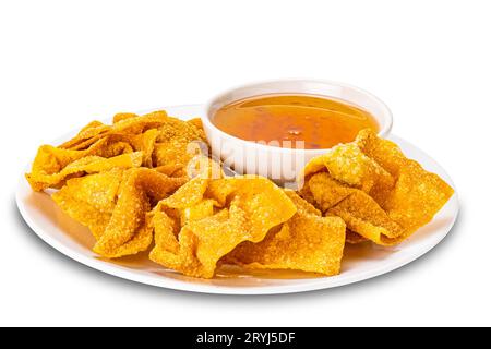 Pile de délicieux wontons frits faits maison croustillants dans une assiette en céramique blanche et sauce sucrée dans une tasse en céramique blanche. Banque D'Images