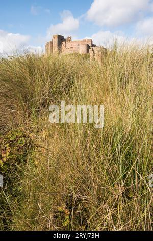 Château de Bamburgh sur la côte ne de l'Angleterre dans le Northumberland vu des dunes de sable sur le rivage. Banque D'Images