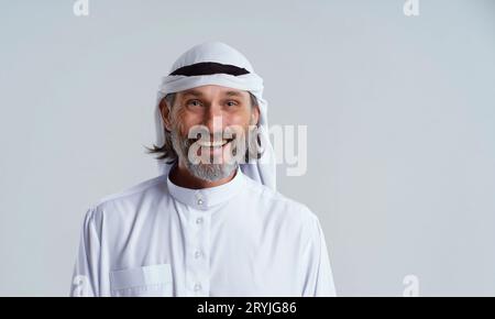 Souriant, heureux homme arabe en dishdasha, vêtements traditionnels portés par les hommes musulmans au Moyen-Orient, isolé sur fond blanc W Banque D'Images