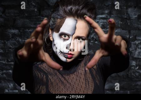 Fille de la mort avec le maquillage de crâne étirant les mains vers la caméra. Banque D'Images