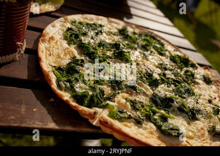 Tarte flambée alsacienne aux épinards et au fromage sur une table dans un restaurant en plein air Banque D'Images