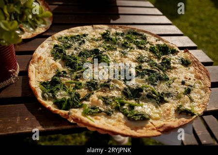 Tarte flambée alsacienne aux épinards et au fromage sur une table dans un restaurant en plein air Banque D'Images