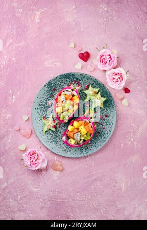 Salade traditionnelle de fruits de la Saint Valentin avec des morceaux de fruits exotiques servis dans des bols de fruits de dragon et décoré avec des fruits étoilés sur un Banque D'Images