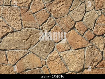 Mur en pierre de granit, arrière-plan. Mosaïque structure de surface, faite de roches de granit (briques). La texture murale de couleur jaune et marron volcanique Banque D'Images