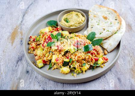 Couscous de légumes marocain traditionnel avec pain pita et houmous servi comme gros plan sur une assiette de Nordic Design Banque D'Images