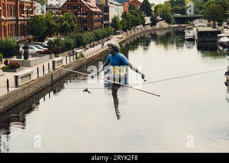 Bydgoszcz, Pologne - août 2022 Rivière Brda à Bydgoszcz Homme traversant une sculpture de rivière , d'un homme en équilibre sur un fil de fer, vieux grana Banque D'Images