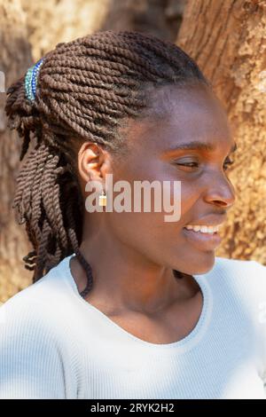 jeune femme afro-américaine avec portrait de tresses, elle sourit et porte une blouse blanche Banque D'Images