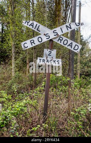 Ancien signe de passage à niveau sur fond d'arbres de printemps Banque D'Images