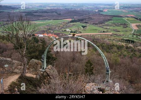 Donnersberg, Allemagne - 9 avril 2021 : Aigle doré au sommet d'Adlerbogen, Eagle Arch, sur une montagne surplombant un petit village et des champs un jour de printemps Banque D'Images