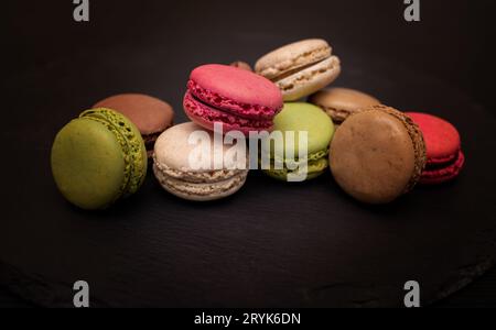 Macaroni coloré sur un fond d'ardoise noire. Gros plan dans différentes positions placées. Banque D'Images