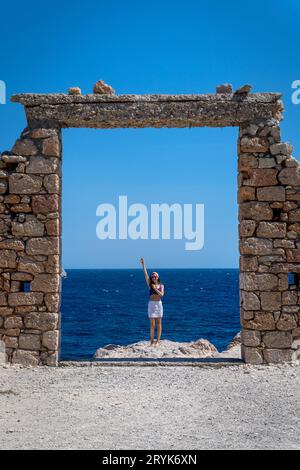 Jeune femme habillée en crochet à la porte en pierre à Paralia Firopotamos, Milos Banque D'Images