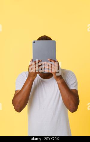 Anonymat incognito concept en ligne. Personne afro-américaine anonyme tenant la tablette PC dans les mains, avec le visage caché isolé sur b Banque D'Images