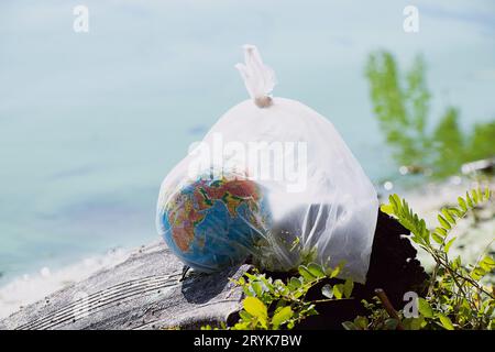 Un globe dans un sac en plastique repose sur un pneu mis au rebut près de l'eau en Ukraine, de la pollution environnementale, de l'écologie, du réchauffement climatique Banque D'Images