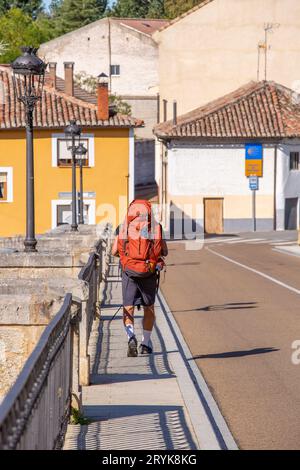 Pèlerins marchant le Camino de Santiago, le chemin de St James route de pèlerinage à travers la campagne espagnole laissant la ville de Carrion par le vieux pont Banque D'Images