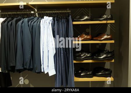 Les chemises, pantalons, vestes et chaussures pour hommes sont suspendus et allongés sur le comptoir d'un magasin. Gros plan. Banque D'Images