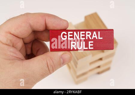 Concept commercial. Dans les mains d'un homme, il y a une plaque de bois rouge avec l'inscription - RÈGLE GÉNÉRALE Banque D'Images