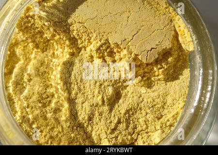 Un pot ouvert d'un gommage facial au curcuma jaune montrant sa texture. Banque D'Images