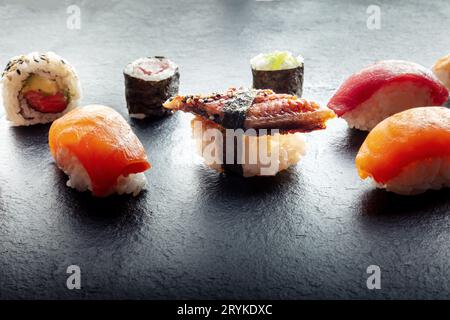Sushi sur une assiette en ardoise noire. Nigiri avec anguille, saumon et thon, rouleau, maki etc Banque D'Images