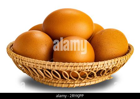 Groupe d'œufs de poule frais dans le panier banboo isolé sur fond blanc. Banque D'Images