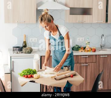 Une femme est debout à la table de cuisine pour préparer un dîner de pâte et de légumes. Cuisine italienne traditionnelle. Banque D'Images