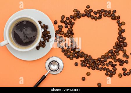 Tasse de café sur une soucoupe avec des grains de café pliés en forme de coeur Banque D'Images