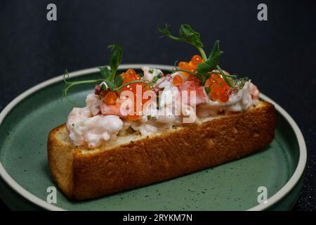 sandwich ouvert de rouleau de homard dans l'assiette avec fond noir Banque D'Images