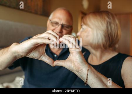 Un couple âgé montre un cœur avec ses mains comme un signe d'amour. Gros plan. Banque D'Images