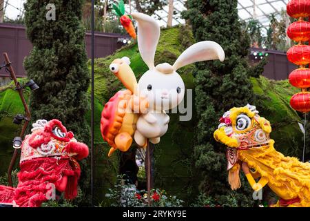 Joli et adorable, un lapin et une tortue ressemblant à des dessins animés émergeant de fleurs dans les jardins au bord de la baie Banque D'Images