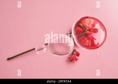 Trois gouttes de gel transparent cosmétique sur fond rose. La texture du sérum. Banque D'Images