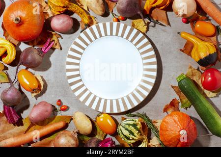 plan d'automne posez sur un fond gris avec des citrouilles, des betteraves, des feuilles d'automne, des feuilles d'automne, des assiettes et des légumes d'automne. Banque D'Images