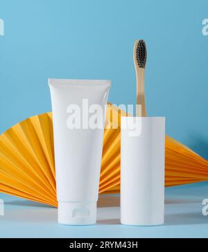 Brosse à dents et tube de dentifrice en plastique blanc sur fond bleu Banque D'Images