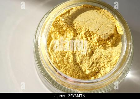 Un pot ouvert d'un gommage facial au curcuma jaune montrant sa texture. Banque D'Images