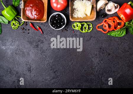 Ingrédients pour la cuisson des pizzas. Sauce tomate, poivron, olives, fromage, champignons et basilic sur fond noir. Banque D'Images