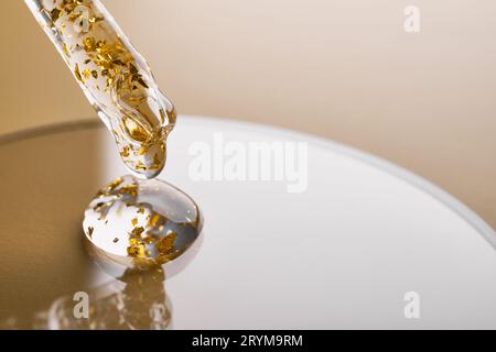 Pipetez et gels de produits cosmétiques dorés dans une boîte de Pétri sur fond beige Banque D'Images